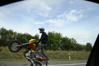 Motorrad Artistik. Ein Motorradfahrer macht einen Wheelie und fährt nur mit dem Hinterrad auf einer öffentlichen Autobahn.