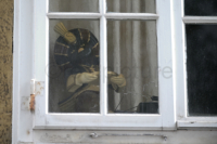Eine alte Sarotti-Mohr Werbefigur steht wie weg gestellt, - aber aufgehoben, im Fenster des ersten Obergeschosses eines Wohnhauses.